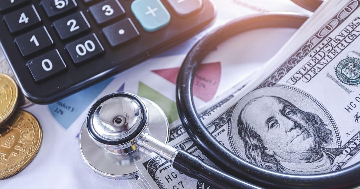 A stethoscope on top of American dollars with a calculator