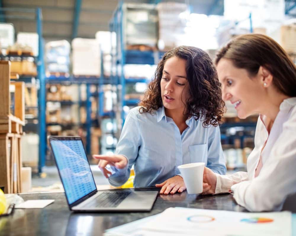 Two people in business attire discusing something at a laptop