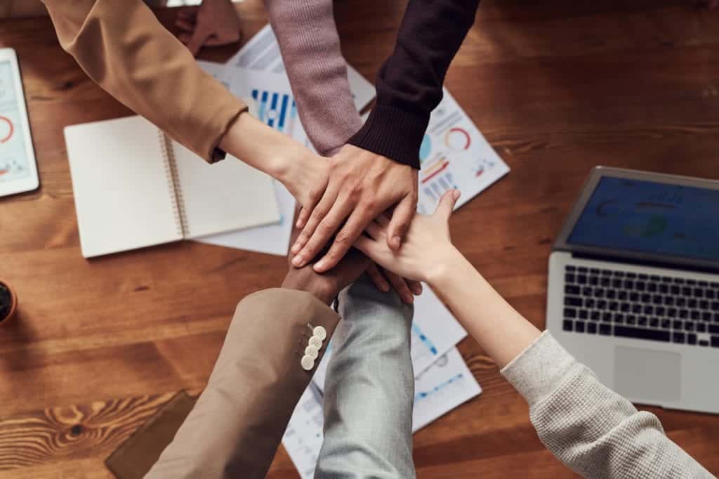 Office workers put hands on top of each other over paperwork