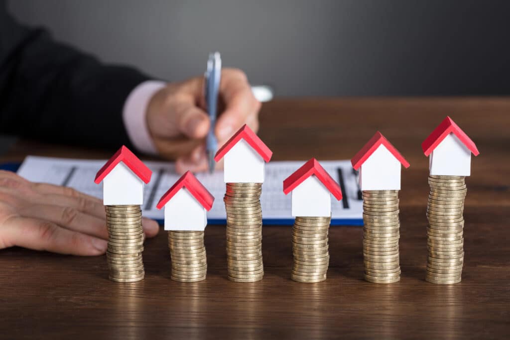 Piles of coins with toy houses on top