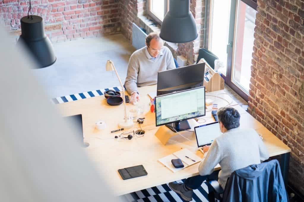 Photo taken from a second story of two business men working at desk top computers