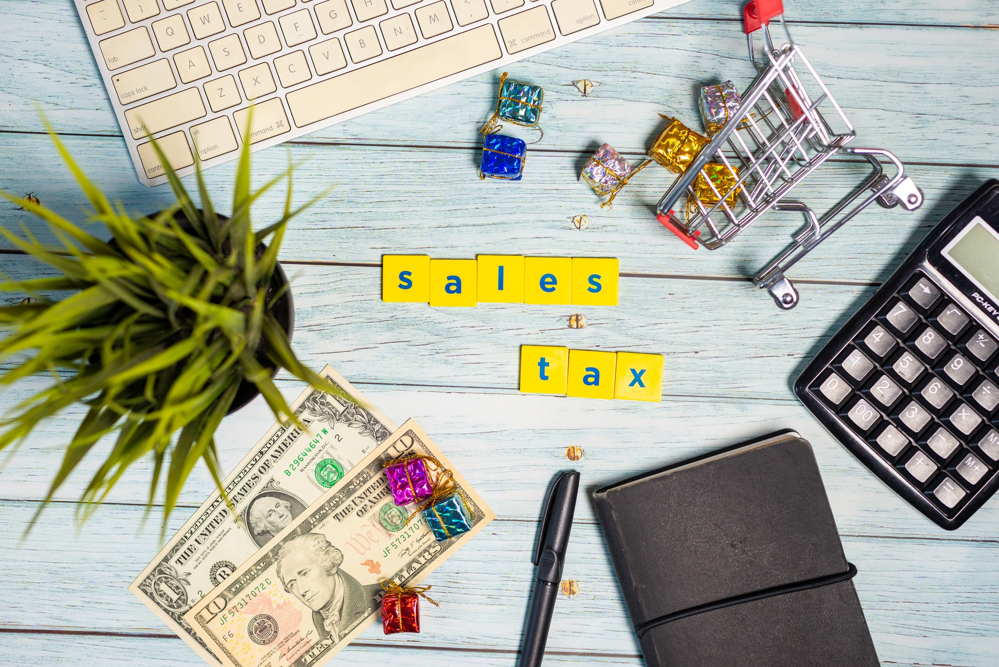 Desk with computer keyboard, money, pen, notebook, shopping art toy