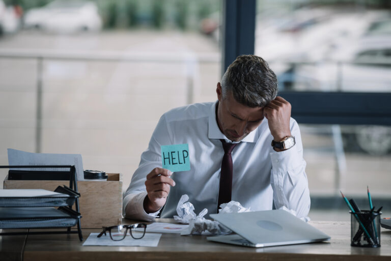 A stressed business owner at a cluttered desk, symbolizing financial challenges and uncertainty following the Bench Accounting shutdown.